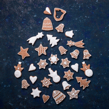 Homemade gingerbread cookie decorated with white icing on a blue background laid out in the shape of...