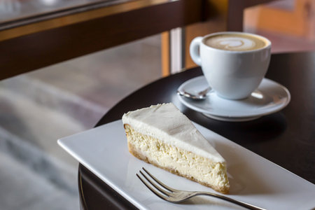 Cappuccino with a heart on a foam and cheesecake on a white plate - a beautiful breakfast in a cafe...
