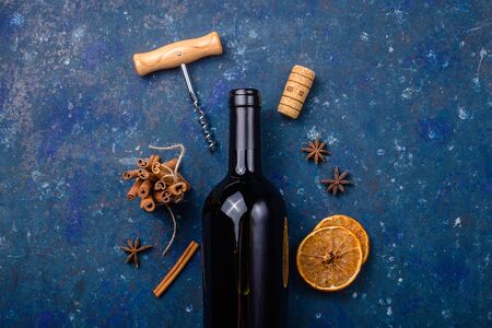 Bottle of red wine with a corkscrew and ingredients for making mulled wine on a dark blue background. Winter drink conceptの写真素材
