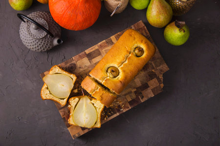 Homemade pie with whole pears on a wooden board on a gray texture table. Top view