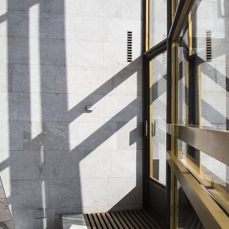 Shadows in a bright interior with marble walls on a bright sunny day. Background and trending shadow lines from door and windowsの写真素材