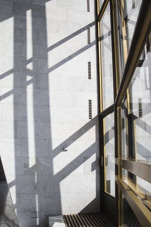 Shadows in a bright interior with marble walls on a bright sunny day. Background and trending shadow lines from door and windowsの写真素材
