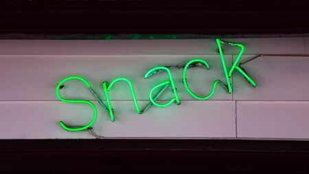Green vibrant neon sign with the word Snack over a street food restaurantの写真素材