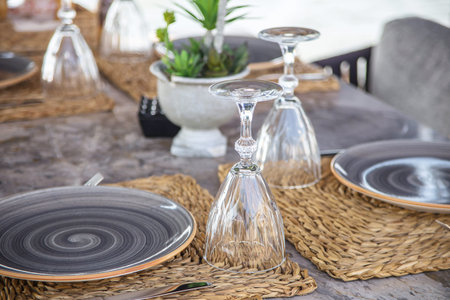 Stylish marble cafe table by the sea with large plates and modern glasses. Travel, vacation and food...