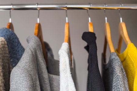 Autumn female gardera on hangers of a sweater and a coat of yellow and gray colors