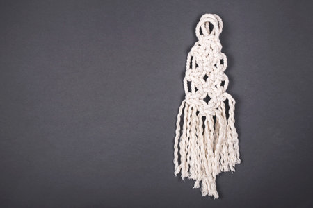 White hand made macrame on minimal gray background. Top view, flat lay, copy space.