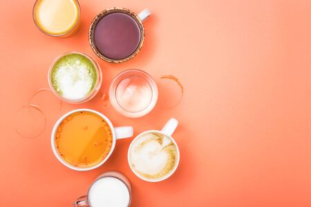 Different drinks cappuccino, tea, sea buckthorn juice, milk, water, orange juice and matcha on a bright coral pink background. Top view, flat lay, copy space.の写真素材