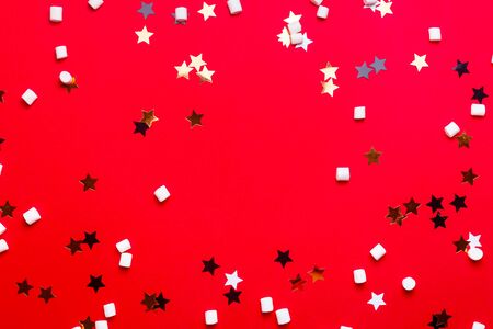 White, black and gold stars and marshmallow pads on a bright red background. Christmas and New Year concept background.の写真素材