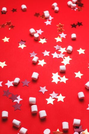 White, black and gold stars and marshmallow pads on a bright red background. Christmas and New Year concept background.の写真素材