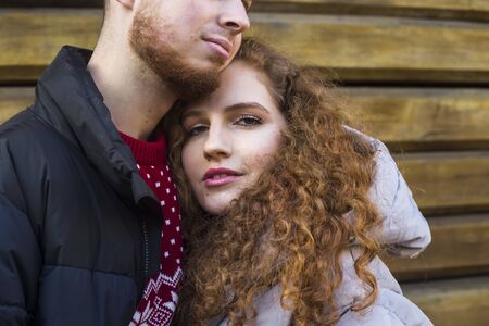 Portrait of a young modern couple in love. Curly girl looking at the camera hugging her boyfriend on a date.の写真素材