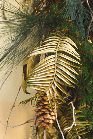 Stylish modern Christmas decorations with golden leaves and cones on fir branches.