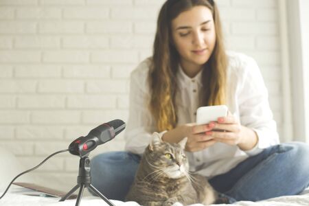 Girl records a podcast with a microphone at home. Modern technologies for creating content for bloggers and influencers.の写真素材