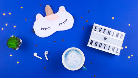 A mask for sleeping, a diary for notes and a cup of matches on a blue background. Evening routine...