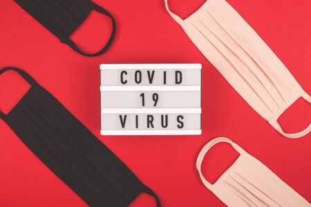 Pink and black medical masks on red. Layout of the coronovirus. Covid 19 inscription. Top view. Quarantine concept.の写真素材