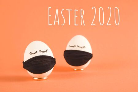 Easter eggs with Corona virus COVID19 protection concepts. Easter eggs wearing mask for Easter holidays decoration. On a peach background with copyspace.の写真素材