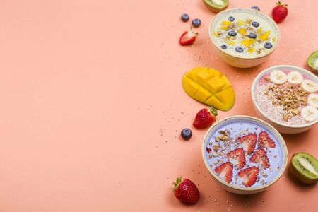 Beautiful multi-colored healthy smoothie bowls with berries and superfoods on a bright background. Summer food for detox concept. Top view, flat lay, copy space.の写真素材