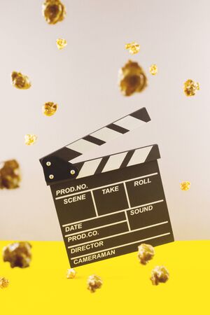 A movie clapper flies among popcorn. The concept of a cinema, relaxing watching movies and TV shows.の写真素材