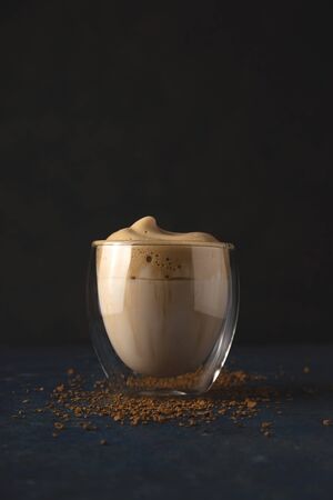 Homemade dalgona coffee made of instant coffee, sugar and milk on a dark background with ice.の写真素材