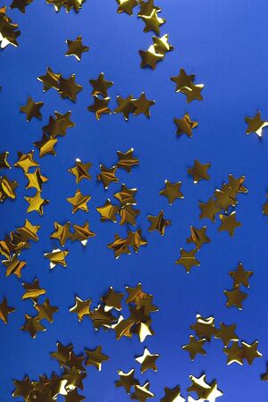 Gold confetti made from stars on blue. Bright festive patternの写真素材