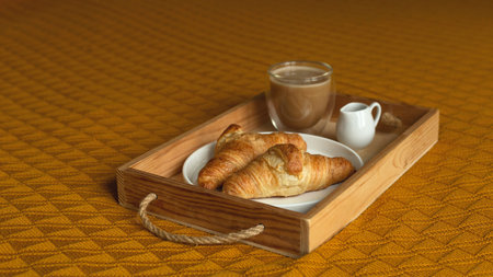 Croissants on a tray with coffee and milkman. Cozy homemade breakfast in bed.