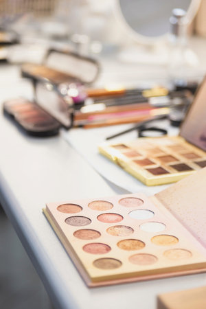 Palette of shadows on the desktop of a makeup artist with brushes and other cosmetics.