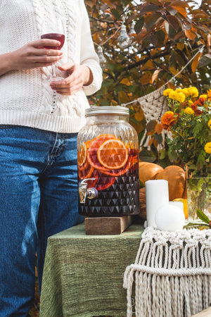 A woman in a sweater holds a glass of wine from a transparent dispenser.の写真素材