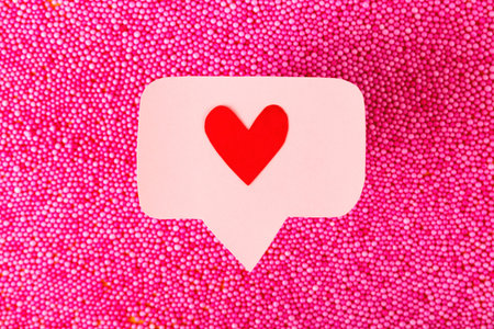 Red like heart icon on a pink pin over pink balls. Many emoji hearts in social networks conceptの写真素材