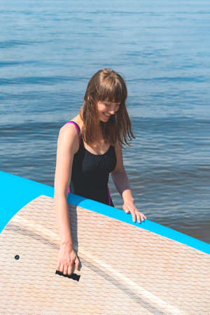 A beautiful woman is engaged in summer active sports on the river on a SUP boardの写真素材