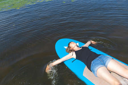A woman lies on a paddle SUP boardの写真素材
