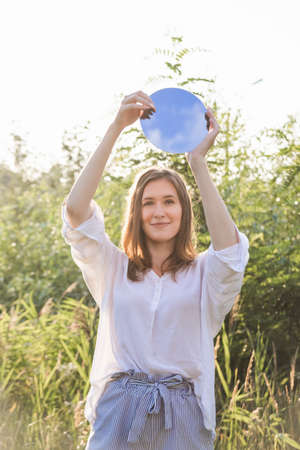 Authentic caucasian girl smiling and holds a small round mirrorの写真素材