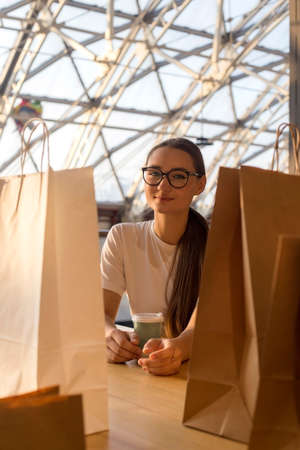 Joyful girl with shopping in a shopping mall at a break food courtの写真素材