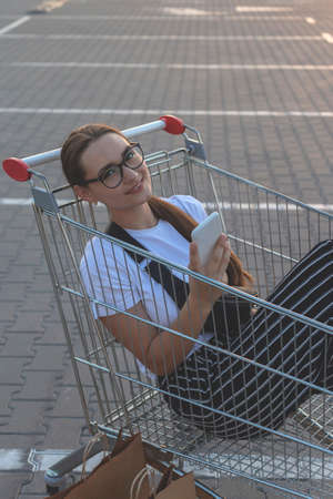 Joyful girl with shopping outside a shopping mall in market trolleyの写真素材