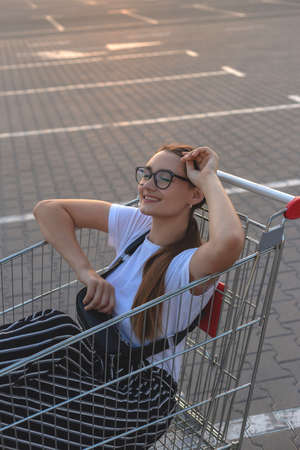 Joyful girl with shopping outside a shopping mall in market trolleyの写真素材
