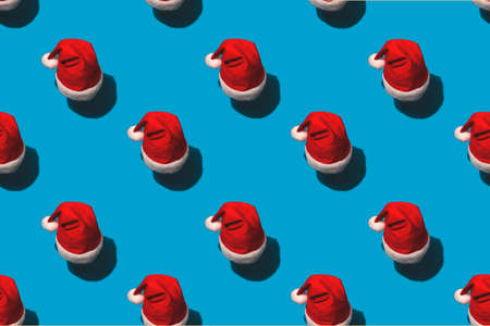 Pattern of bright red santa claus hats on blueの写真素材