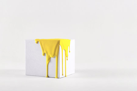 White cube with smudges of bright yellow paint color of the year 2021の写真素材