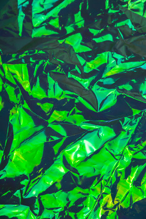 Green crumpled textured holographic trendy dark backgroundの写真素材
