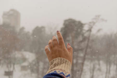 Womans hand reaches for snowflakes during snowfallの写真素材