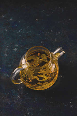 Healing linden herbal tea in a teapot on a dark backgroundの写真素材