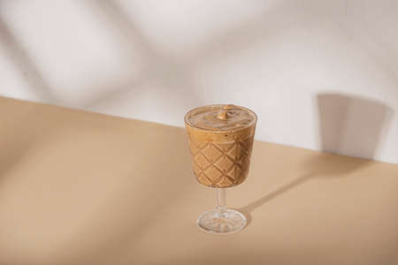 Coffee in a glass on beige background with shadowsの写真素材