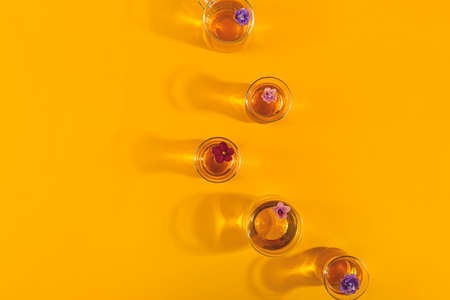 Glass cups of tea with flowers on bright yellow with shadowsの写真素材