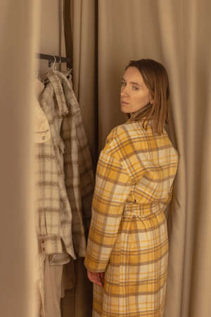 Woman trying on a coat in a fitting room of a clothing storeの写真素材