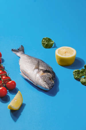 Dorado fish, lemon6 garlic and cherry tomatoes on a bright blue backgroundの写真素材