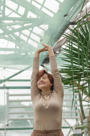 A beautiful plus size girl enjoying standing among the green plantsの写真素材