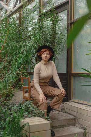 A beautiful plus size girl with red hair among green branches of tropical plantsの写真素材