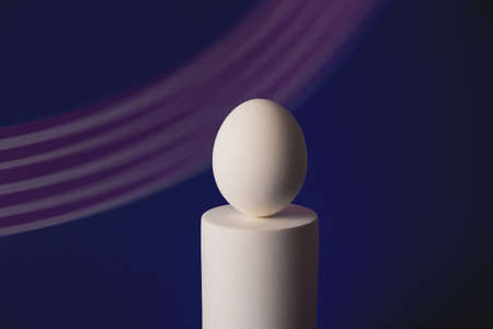 White easter egg on podium in neon and purple lightの写真素材