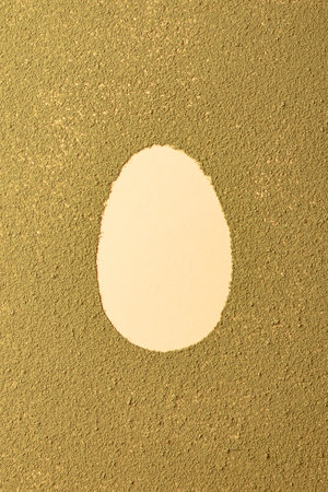 Oval easter egg silhouette made from matcha tea on green textured background. Minimalism