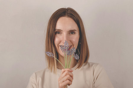 Beautiful caucasian millennial girl holding muscari flowers in her hands. A gift from a child for mothers dayの写真素材