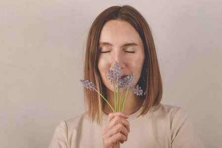 Beautiful caucasian millennial girl holding muscari flowers in her hands. A gift from a child for mothers dayの写真素材