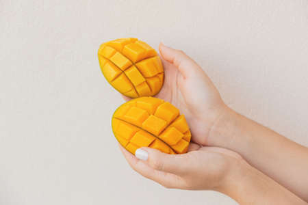 Beautiful slices of chopped mango in female hands. Vegan healthy dessertの写真素材