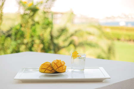 Mango cut in half with a cold drink on white tray on the hotel balcony on vacation.の写真素材